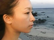 Garota japonesa caminha à beira-mar